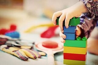 a kid's hands playing with coloured blocks