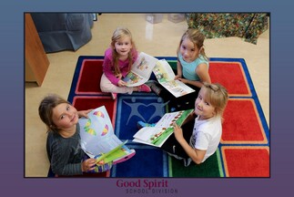 four female students sitting on carpet holding books and looking at camera and smiling