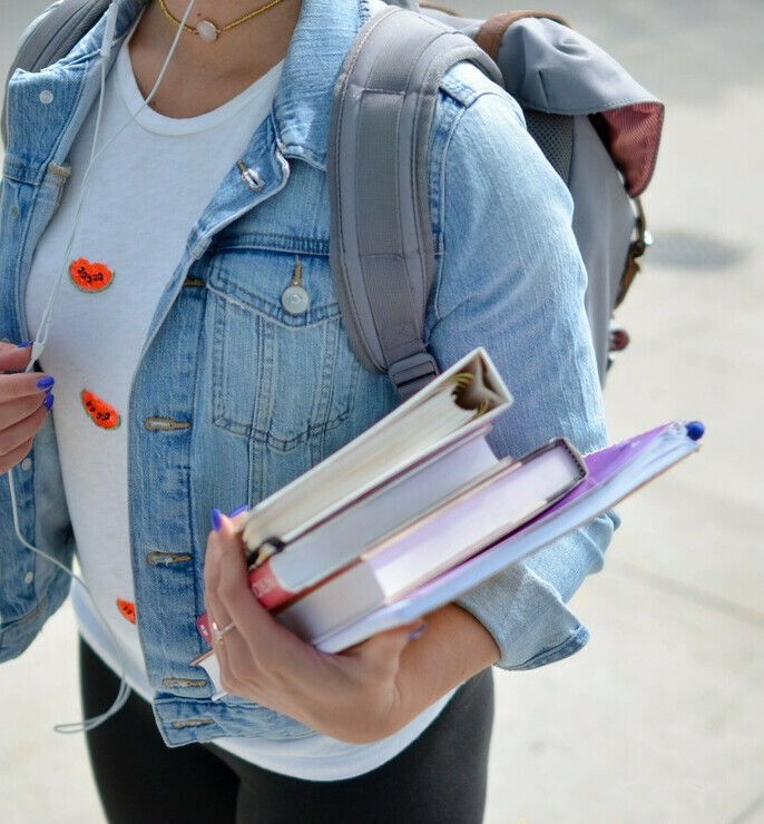 student wearing backpack and holding books